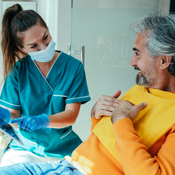 Dentist showing a tablet screen to an older male patient