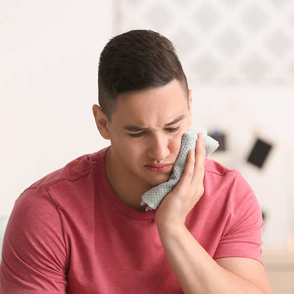 Man holding a cold compress to his cheek