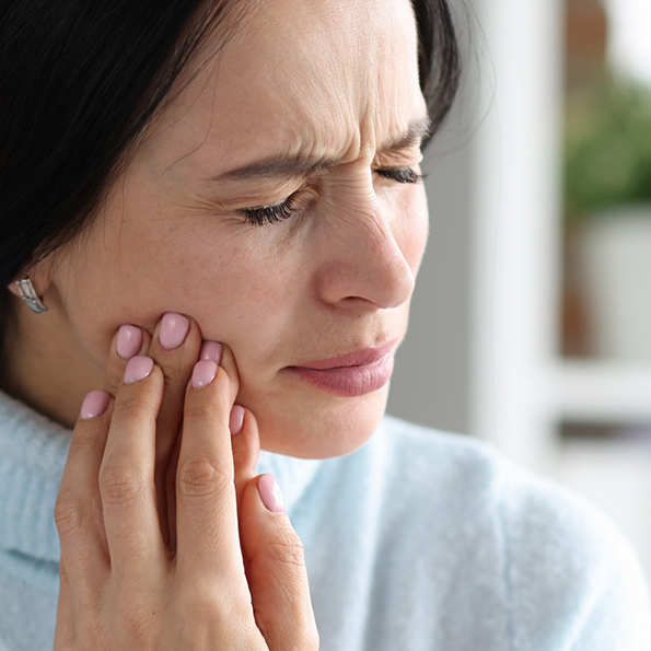 Woman wincing and holding her cheek in pain