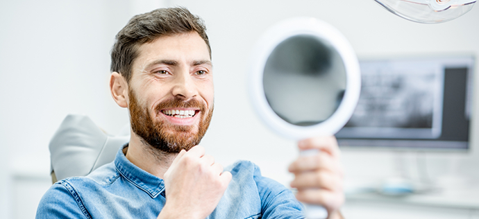 Man in dental chair looking at his smile after restorative dentistry in Warrenton