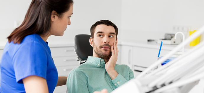 Dental patient holding his cheek in pain right before root canal treatment in Warrenton