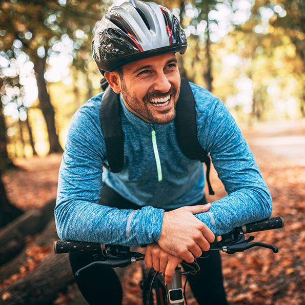 Man smiling while riding his bike through a forest