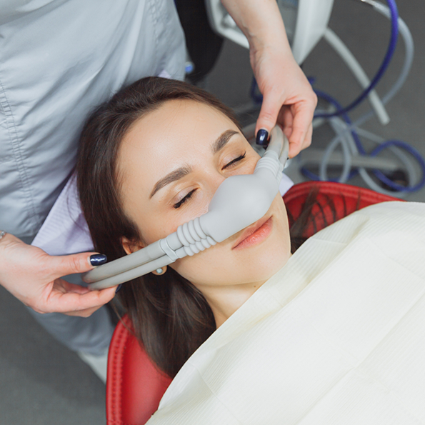 Woman relaxing in dental chair with a nitrous oxide mask over her nose