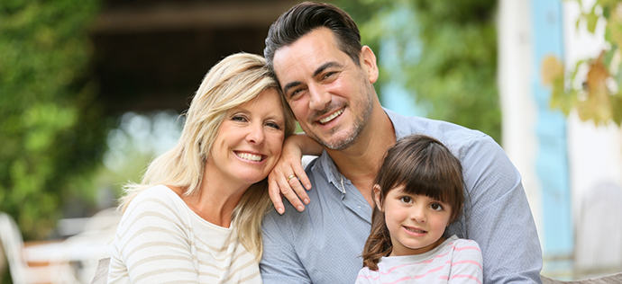 Family of three smiling outdoors