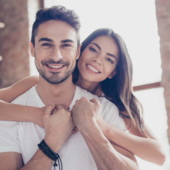 Young woman hugging young man from behind